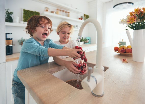 Lapset pesevät hedelmiä keittiössä