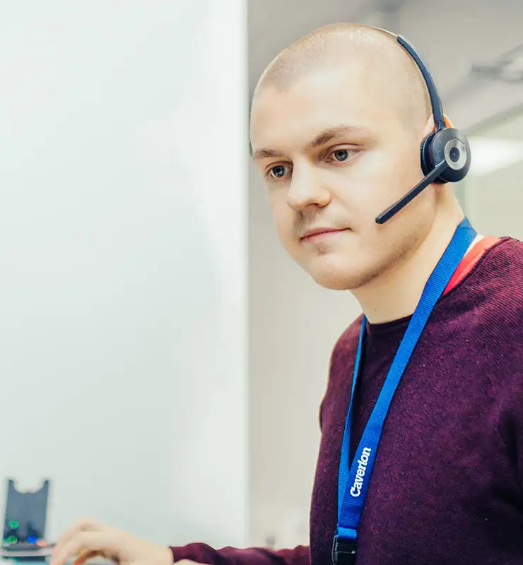 Asiantuntija puhuu puhelimessa ja katsoo tietokoneen näyttöjä